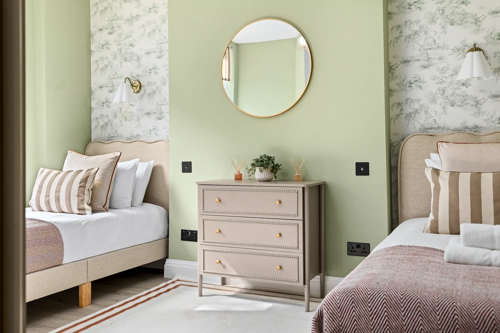 Sage-green bedroom with a round mirror and patterned wallpaper, Airbnb photography London