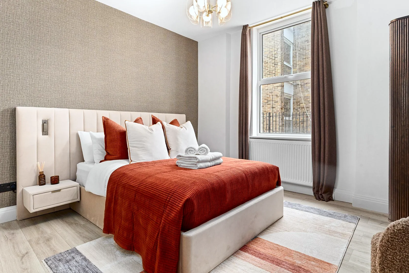 Rust-throw bedroom with panelled headboard, soft light, interior photography London