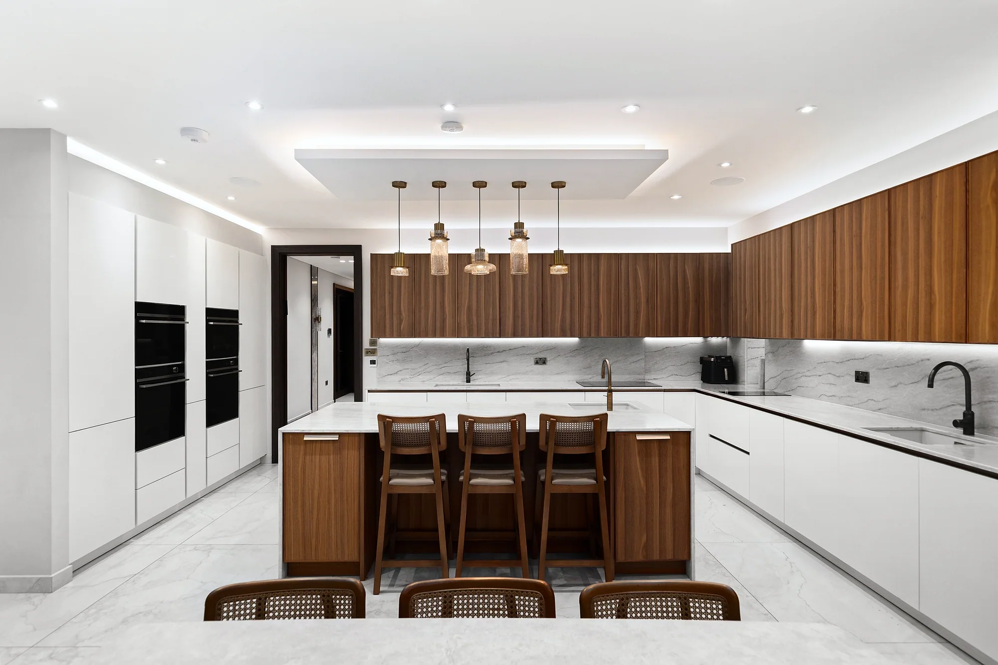 Long kitchen with a walnut island and four stools, kitchen photography London